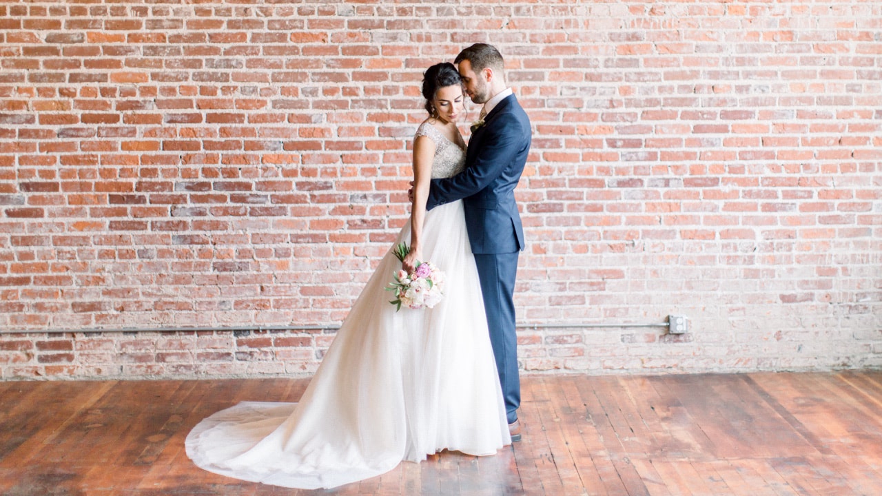 Franciscan Gardens bride and groom hugging in front of exposed brick wall