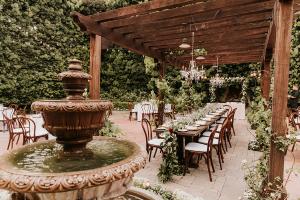 Side view of large elegant fountain and long dining table in Francisco Gardens courtyard