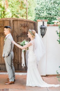 Bride tapping groom's shoulder from behind in front of Franciscan Gardens' gate
