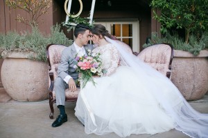 Bride and groom holding each other and a bouquet in a long elegant chair at Franciscan Gardens   